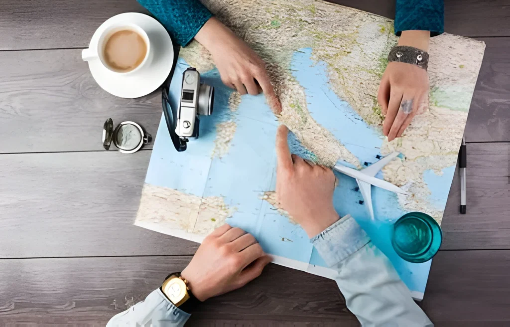 A person planning an eco-friendly travel route on a world map, with minimalism inspired accessories including a camera, a cup of coffee, and a toy airplane