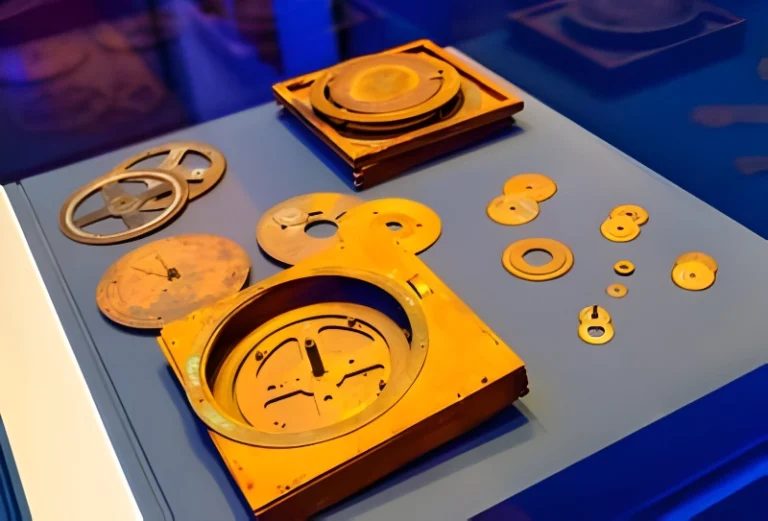 A close-up photo of a collection of rusty, weathered bronze gears and other mechanical pieces scattered across a table.